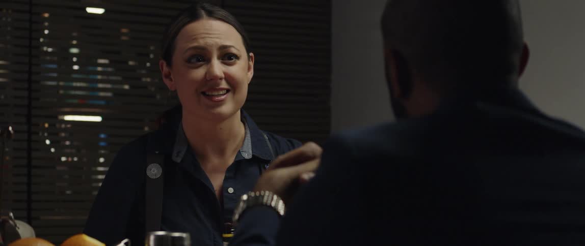 A female bartending smiling and laughing while preparing a drink for a customer