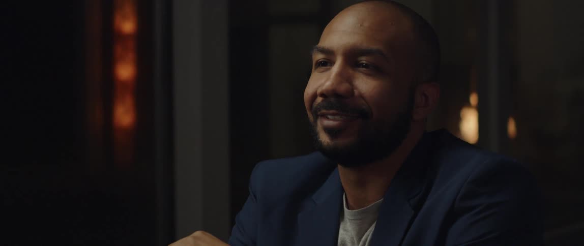 A man is smiling and sitting in a room by himself