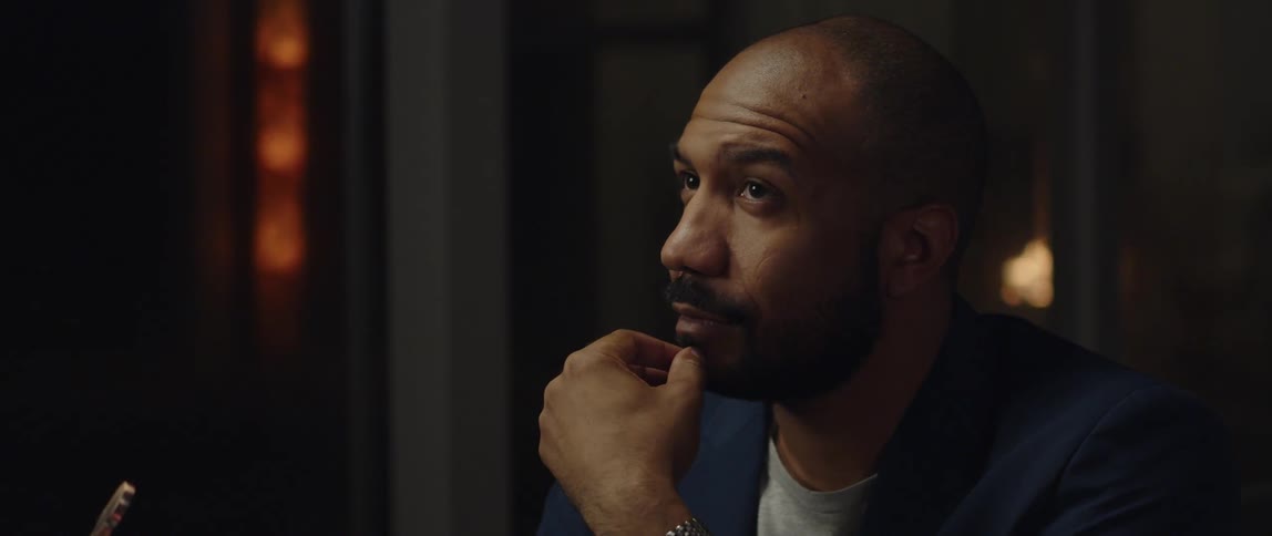 A man sitting stroking his beard and chin as he thinks