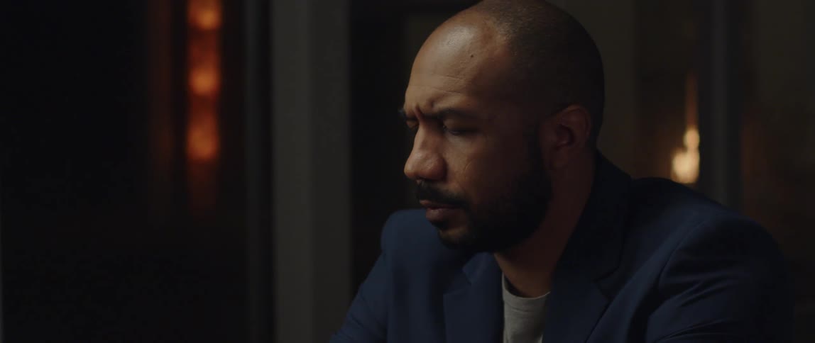 An older black man is drinking alcohol inside