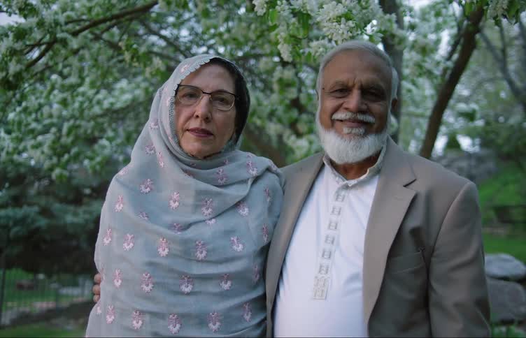 An older couple is smiling outdoors together in the middle of the day