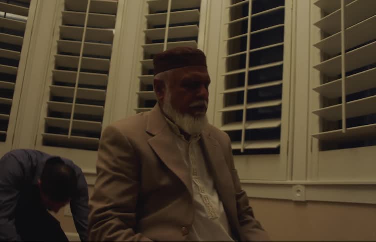 Men with brown jacket white shirt and blue shirt pray at the mosque