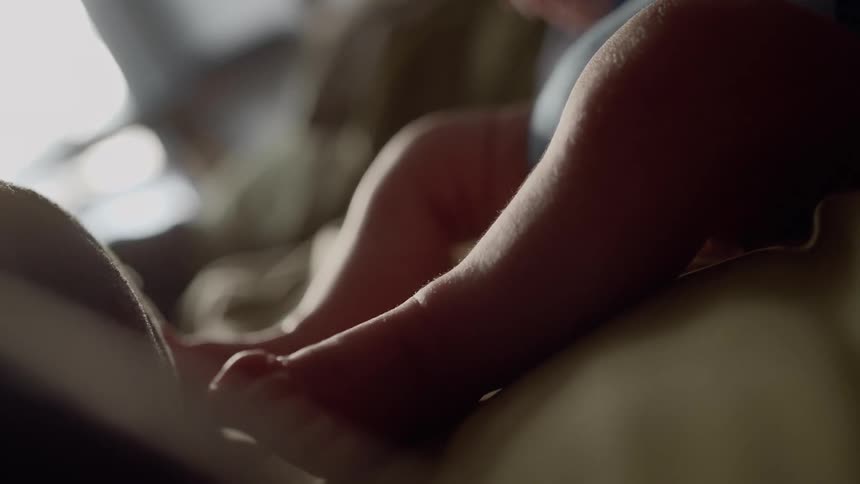 An infant is kicking and sitting on a couch