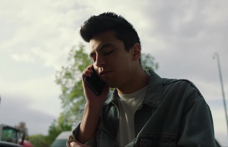 A man is outside and talking on his cell phone