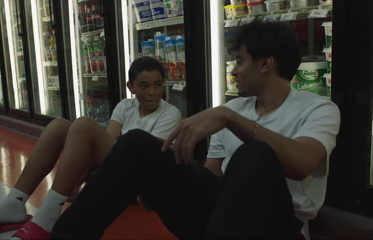 A man and a young boy are sitting together on a grocery store floor having a conversation