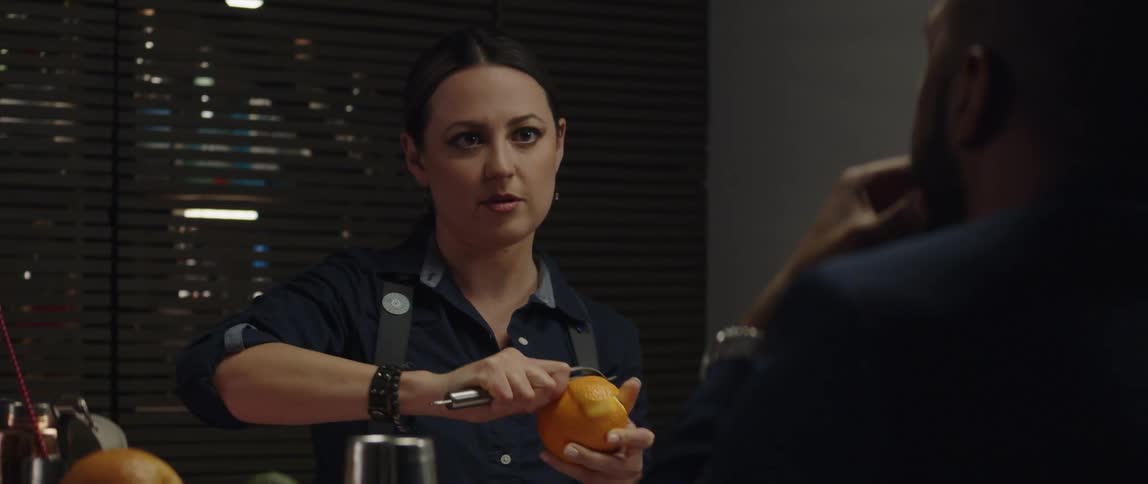 A female bartender cutting an orange behind the counter