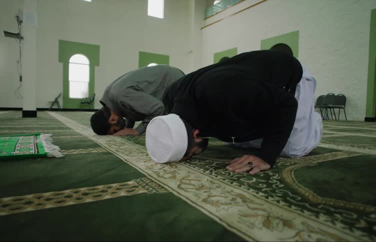 Muslim men with skullcaps pray at the mosque