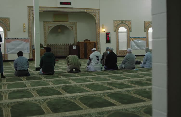 A group of men kneel on a floor and pray