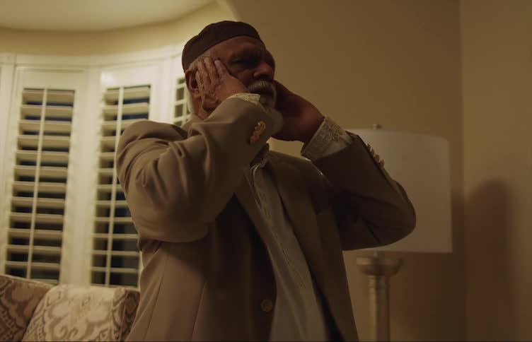 An elderly man chanting a prayer in a living room