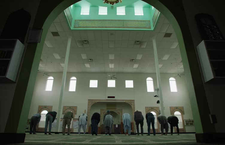Group of people gathering inside a mosque praying and kneeling
