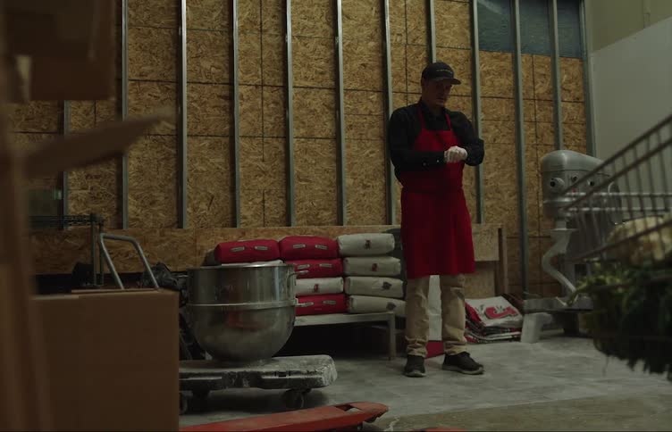 A young white man is working inside of a warehouse
