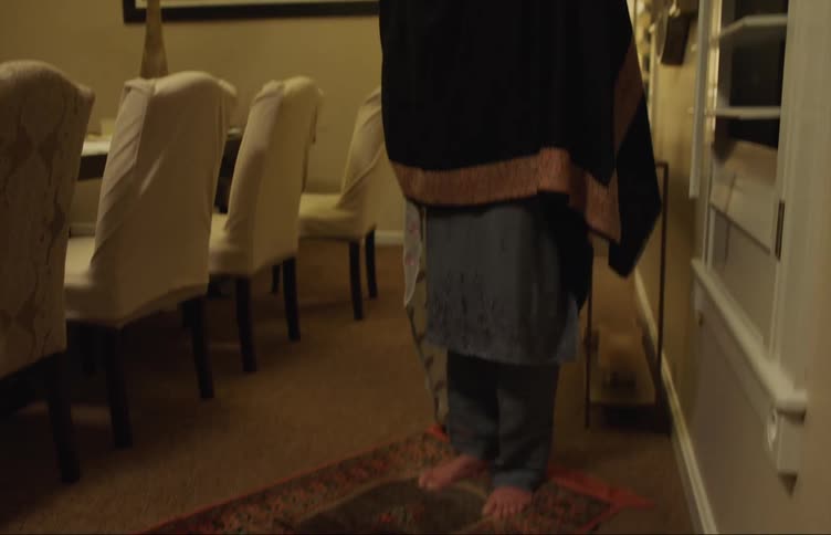 Woman stands on prayer rug in dining room
