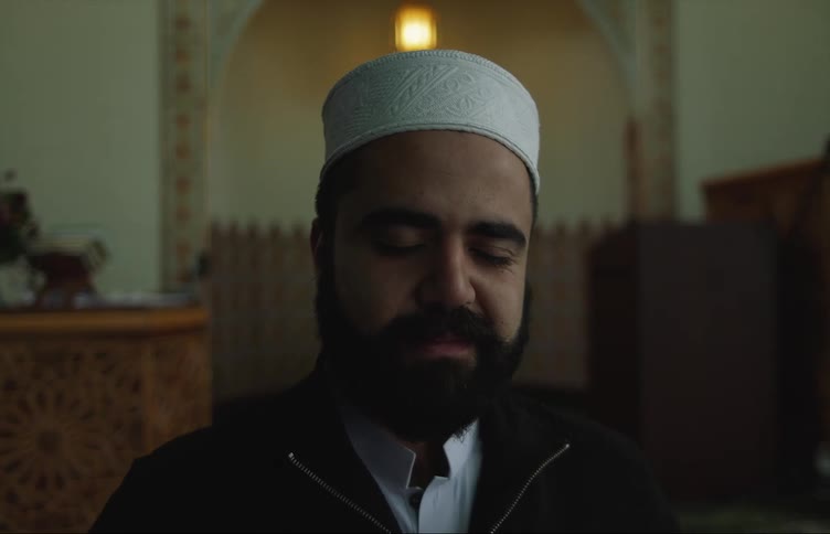 A Muslim man smiling with his eyes closed while in a mosque