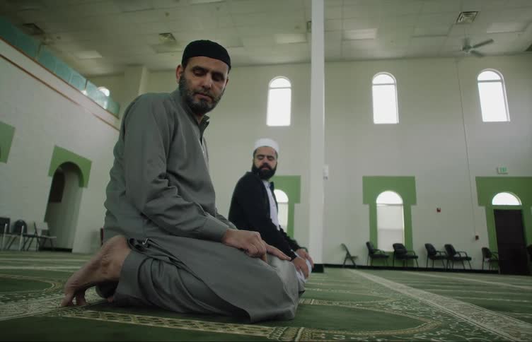 Muslim man with gray shirt prays at the mosque