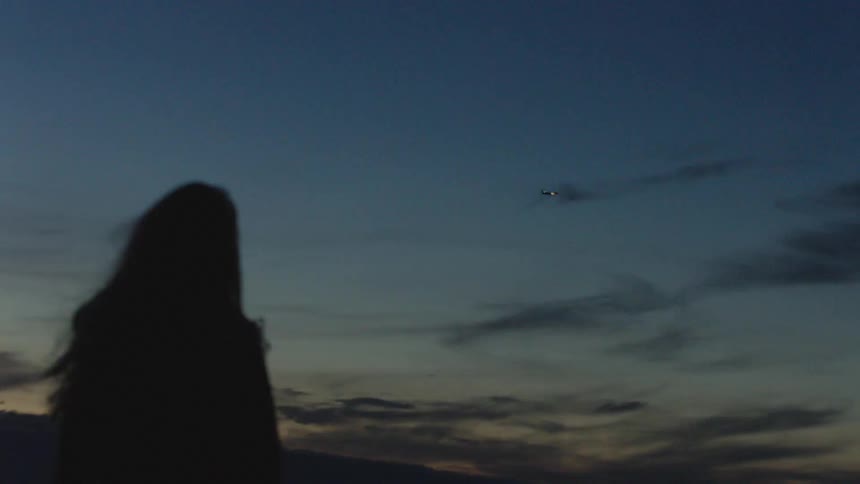 A woman is outdoors watching the sun set