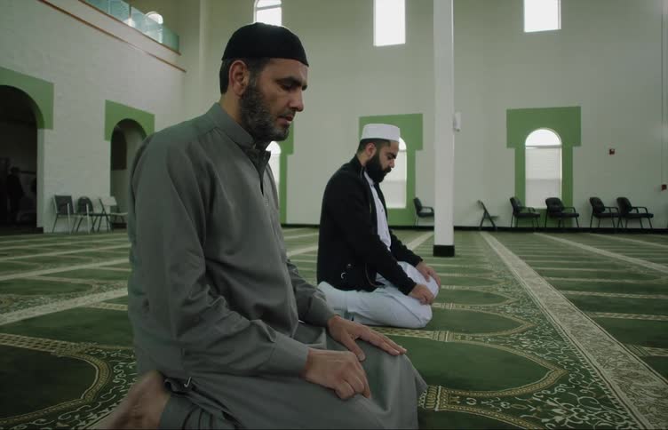 Muslim men with skullcaps and beards pray at the mosque