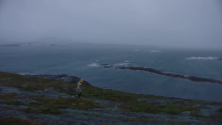 A woman walking along a coast on a cloudy windy day