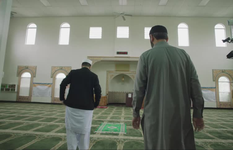 Muslim men with skull caps walk into mosque to pray