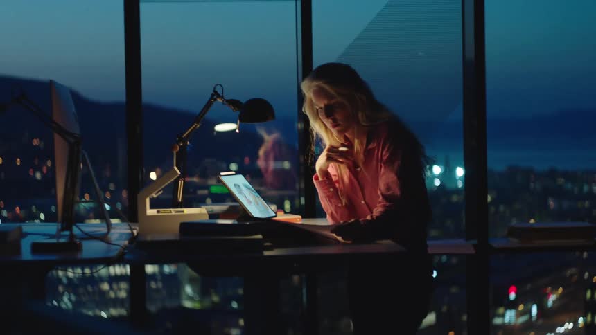 A young woman is working in the office at night time
