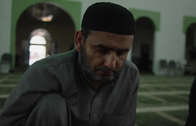 Middle eastern man sitting on the floor of a mosque