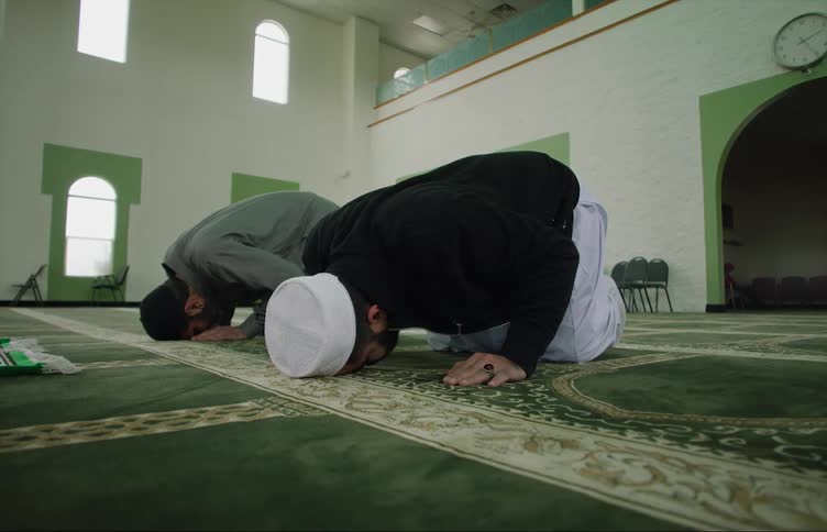Muslim men bow in prayer in a mosque