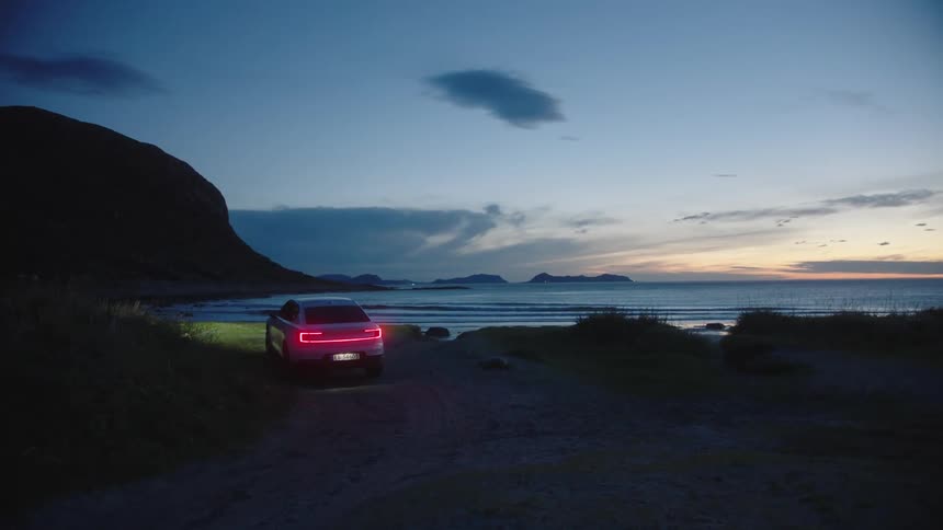 A car is driving near the beach coast at dusk