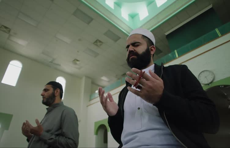 Muslim men with beards and shirts pray at the mosque