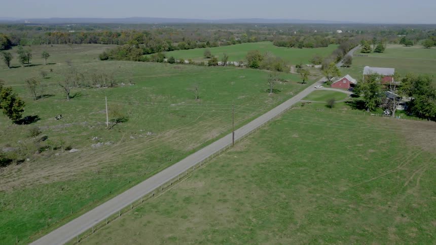 A large green field has a farm on it