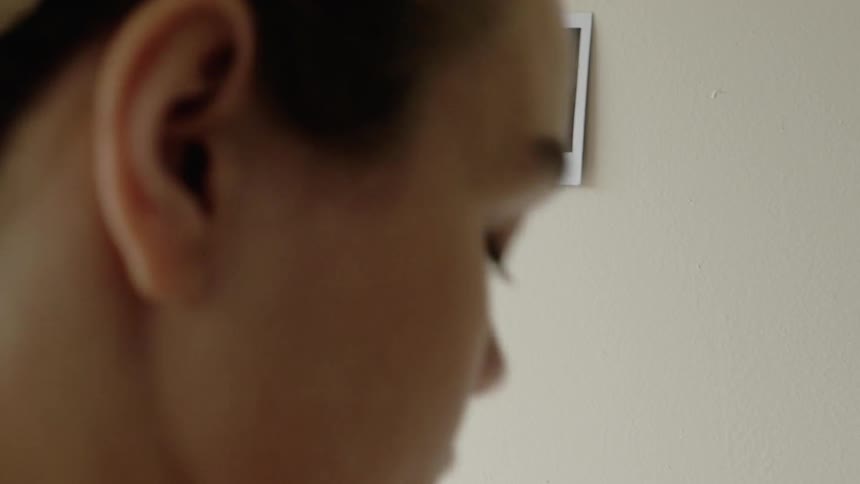 A woman tapes polaroid pictures to the wall