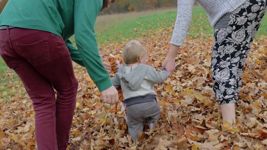 A couple and a child play in some leaves