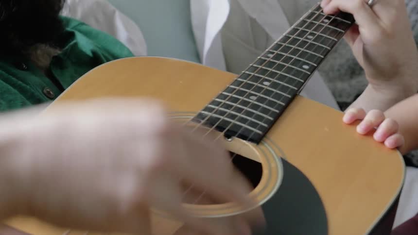 A person is playing a guitar as others watch