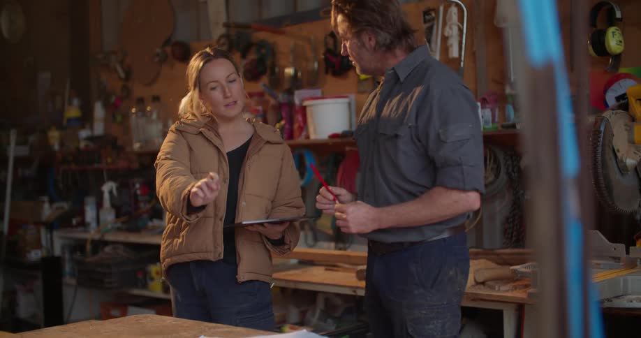 Male and female are working in a garage together and talking