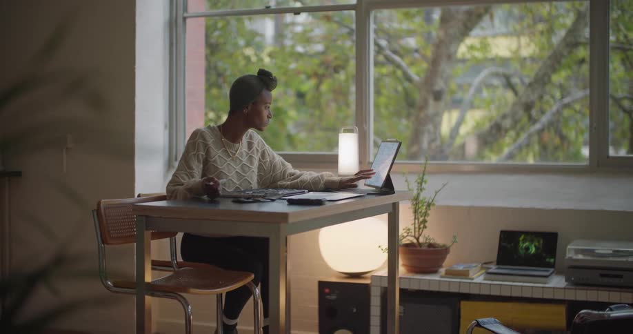 A woman scrolls through her tablet while taking notes in the office