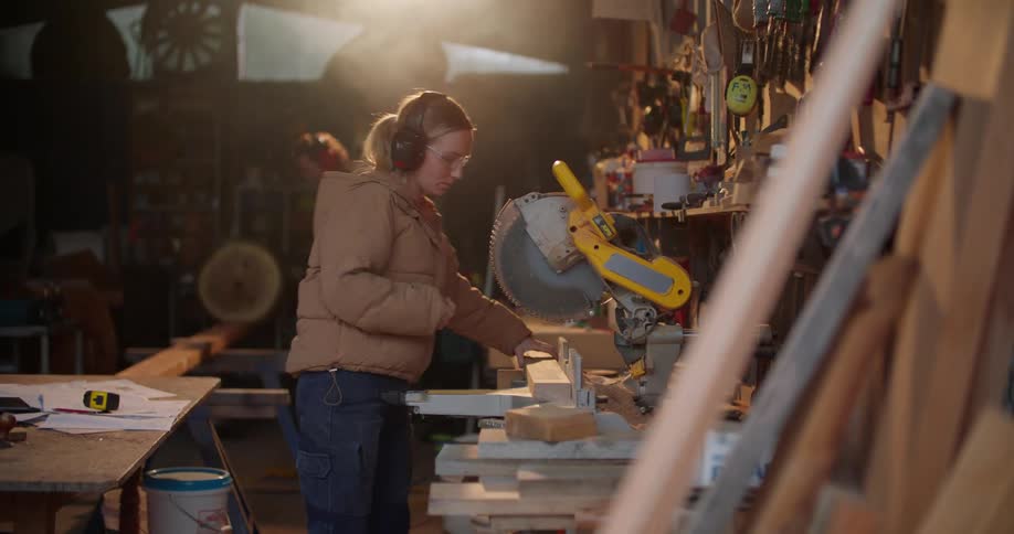 A woman puts on protective headphones before using a circular saw