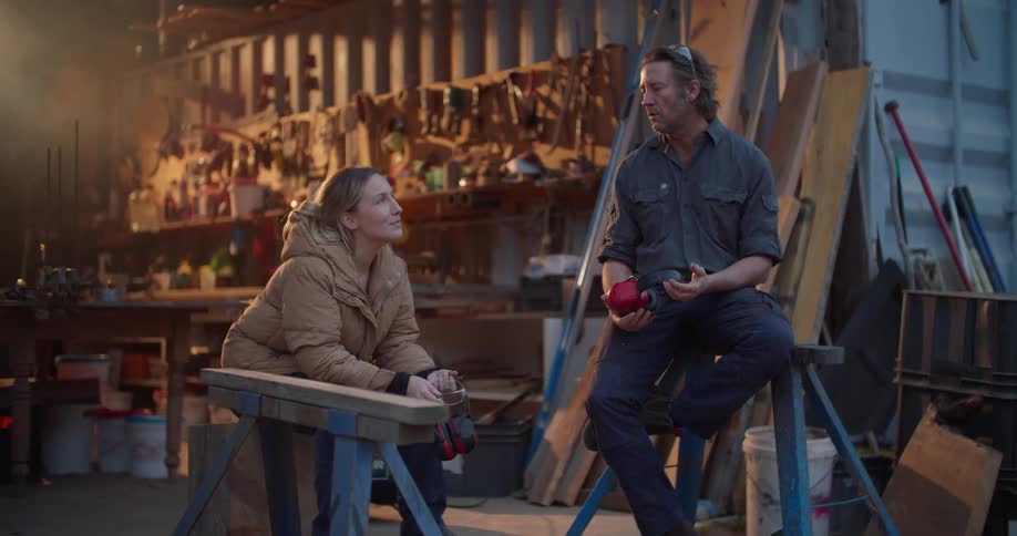 Carpenters take a break and sit on sawhorses while chatting in a garage