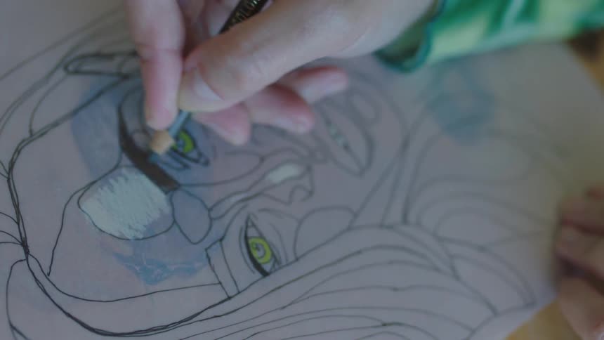 A person is drawing a picture and sitting at a table