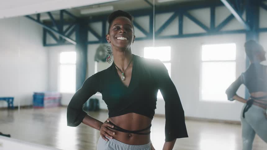 Woman smiles as she poses in dancing studio near large mirror