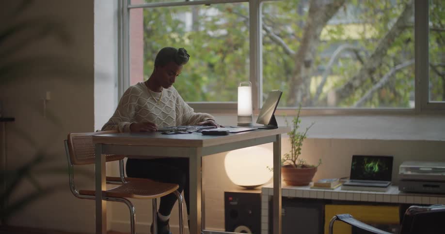 A woman works by herself at a desk with a tablet in a zen office setting