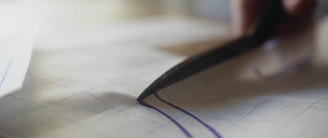 A womans hands can be seen cutting a pattern with scissors