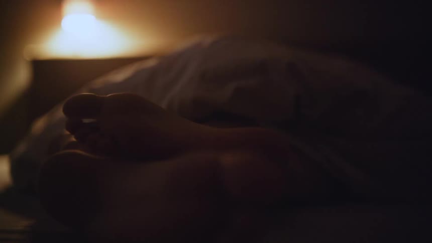 Two feet are touching each other on the bed