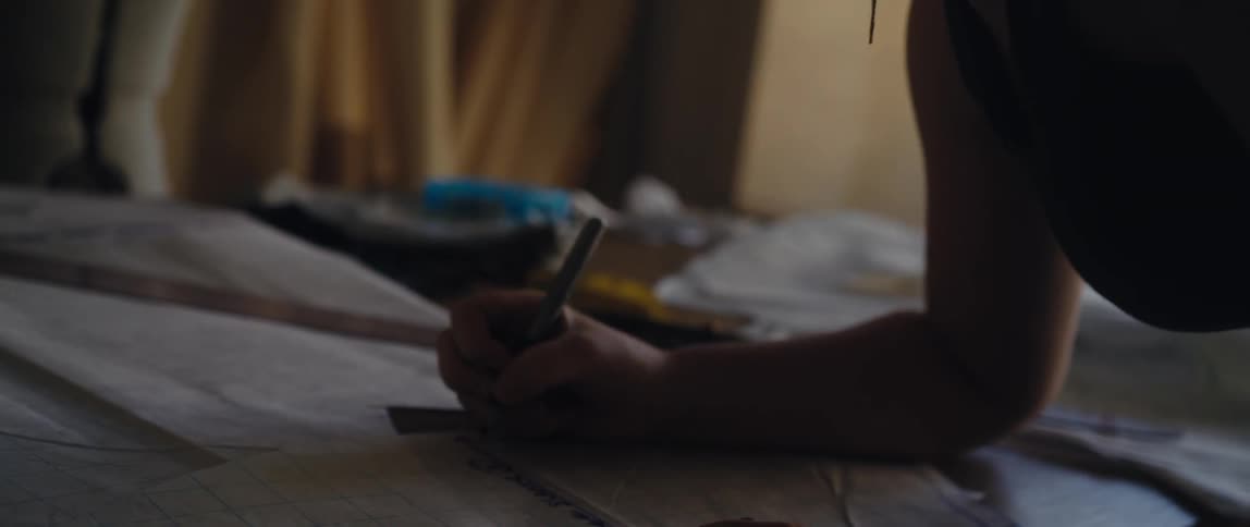 A woman leaning over her worktable marking a design pattern