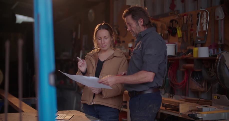 Man and woman stand in workshop discussing plans