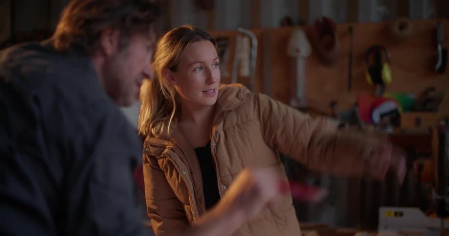 Man and woman examine and discuss plans whilestanding in workshop