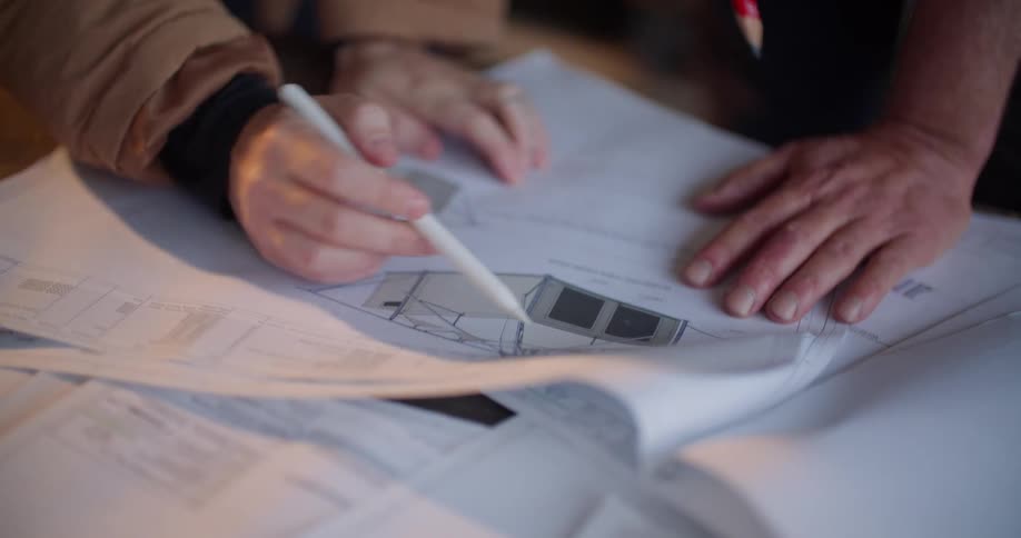 Two people are looking over blueprints and making notes