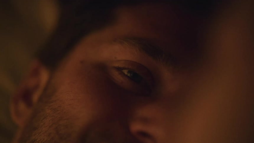 A man smiles at his girlfriend as they lie in bed