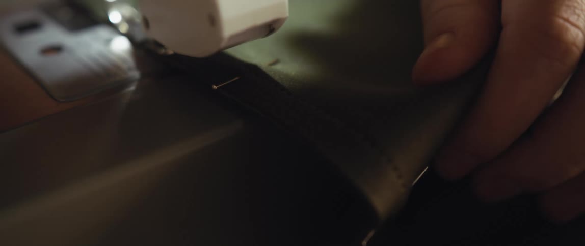 A woman is stitching a seam into a piece of fabric with a sewing machine