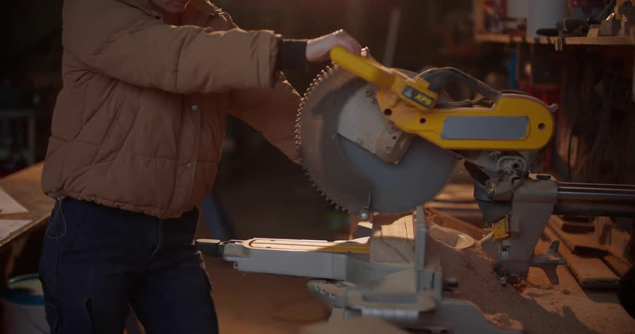 A woman measures a piece of wood on her worktable then turns and uses a circular saw to cut it to size