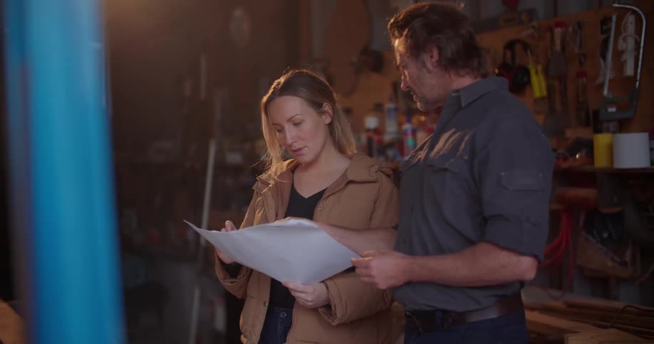 A woman goes over papers while speaking with a contractor in her garage
