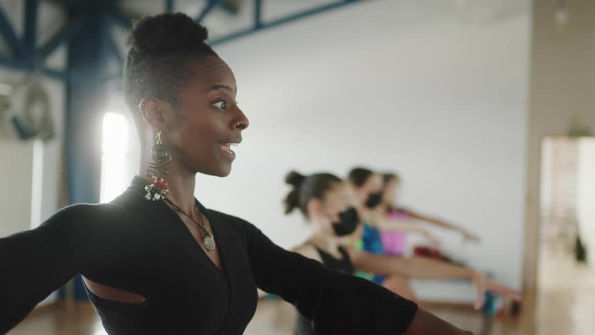 Dance instructor moves through dance pose with her students in a dance studio