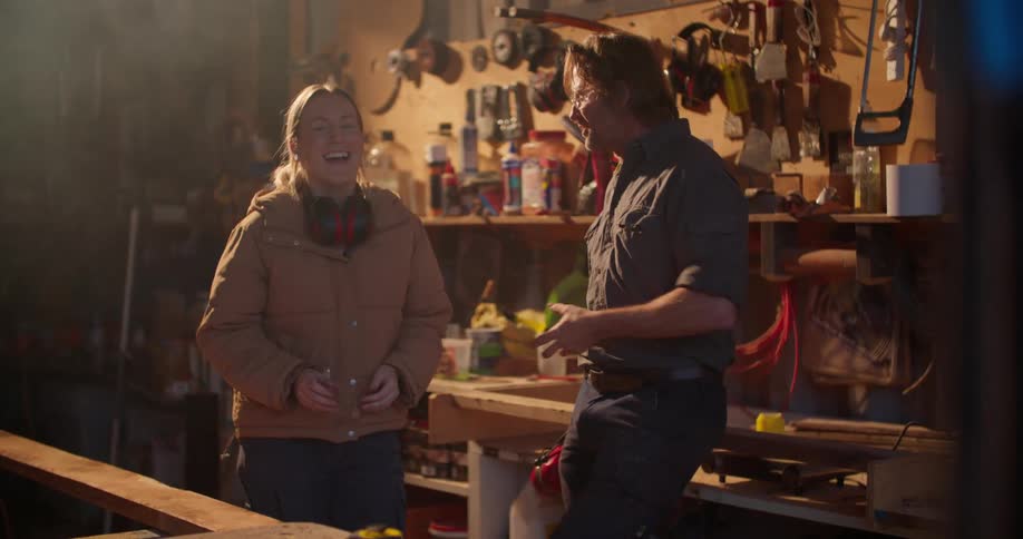 A woman laughs while talking to a man in a workshop